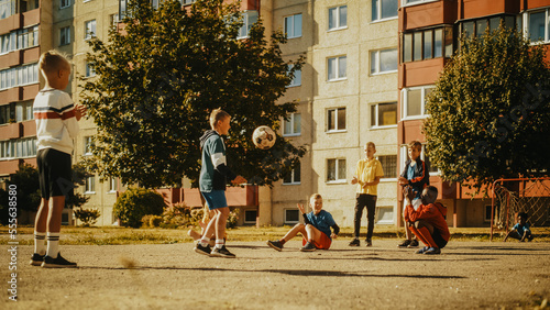 Young Multiethnic Kids Playing with Ball in the Neighborhood. Young Boy Practicing Soccer Drills, Controlling the Ball in the Air. Friends are Clapping and Cheering for Him.