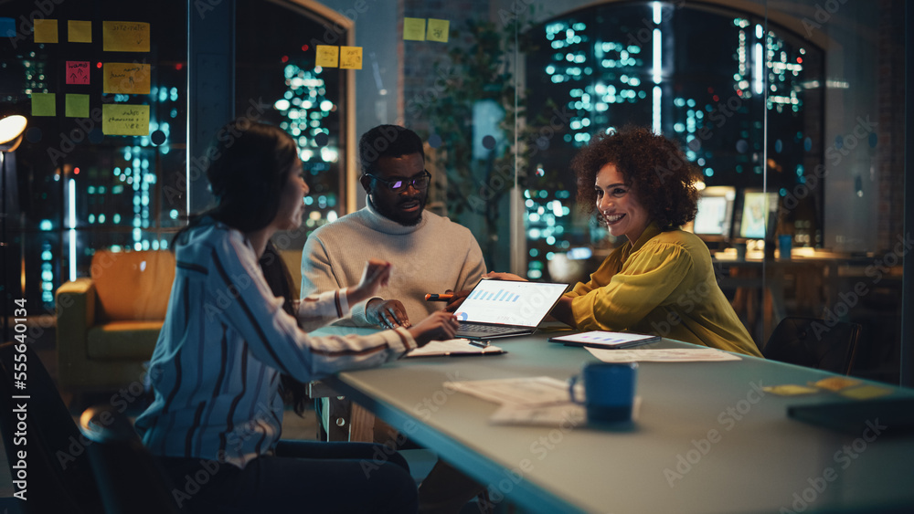 Excited Marketing Manager Leading a Team Meeting in Creative Office Conference Room in the Evening. Confident Multiethnic Female Discussing a New Project Plan with Agency Employees. Excited Marketing Manager Leading a Team Meeting in Creative Office Conference Room in the Evening. Confident Multiethnic Female Discussing a New Project Plan with Agency Employees.