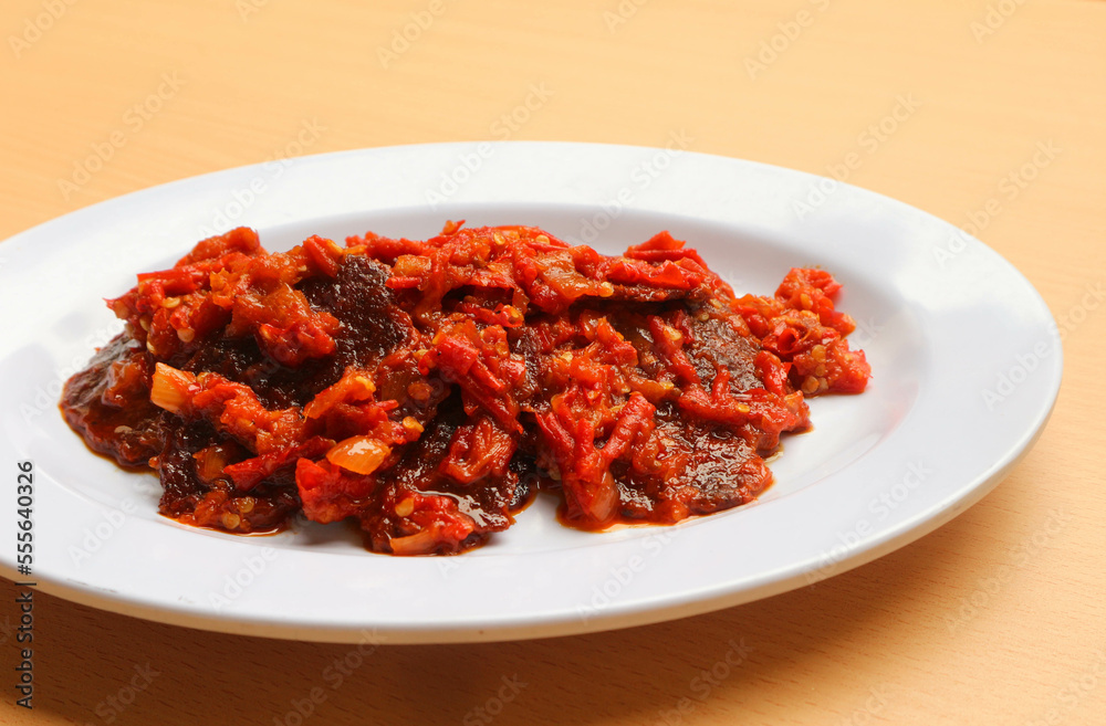 Dendeng balado or jerky beef with spicy seasoning is a traditional cuisine from west sumatera, indonesia. it is made from slice of beef with spicy sauce called sambal. served on plate. Dendeng balado or jerky beef with spicy seasoning is a traditional cuisine from west sumatera, indonesia. it is made from slice of beef with spicy sauce called sambal. served on plate.