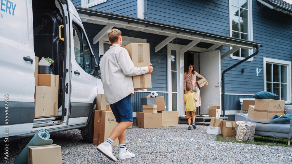 Handsome Man Unloading a Cargo Van Full of Cardboard Moving Boxes. Young Happy Family with a Son Moving to Their Dream Home in the Suburbs. Delivery Transportation Car Sharing Service. Handsome Man Unloading a Cargo Van Full of Cardboard Moving Boxes. Young Happy Family with a Son Moving to Their Dream Home in the Suburbs. Delivery Transportation Car Sharing Service.