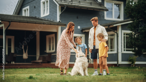 Fotografía Portrait of a Cheerful Family Couple with Kids, Playing and Petting a Beautiful White Golden Retriever Dog