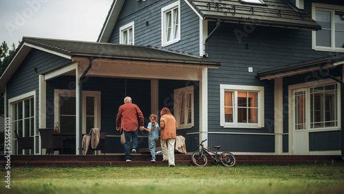 Grandfather and Grandmother Walking Together with Their Granddaughter in Front of their Suburbs House, Holding Hands. Grandparents Spending the Weekend with Kids, Enjoying Family Time with Grandchild.