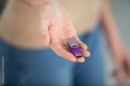 young woman hands holding purple flash drive