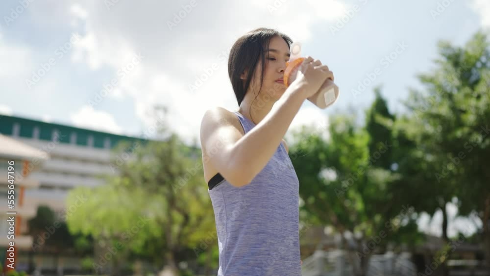 Asian woman, healthy exercising outdoors, She eats protein after exercising Asian woman, healthy exercising outdoors, She eats protein after exercising