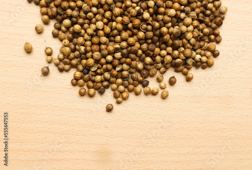 Pile of roasted coriander seeds isolated on brown wooden background