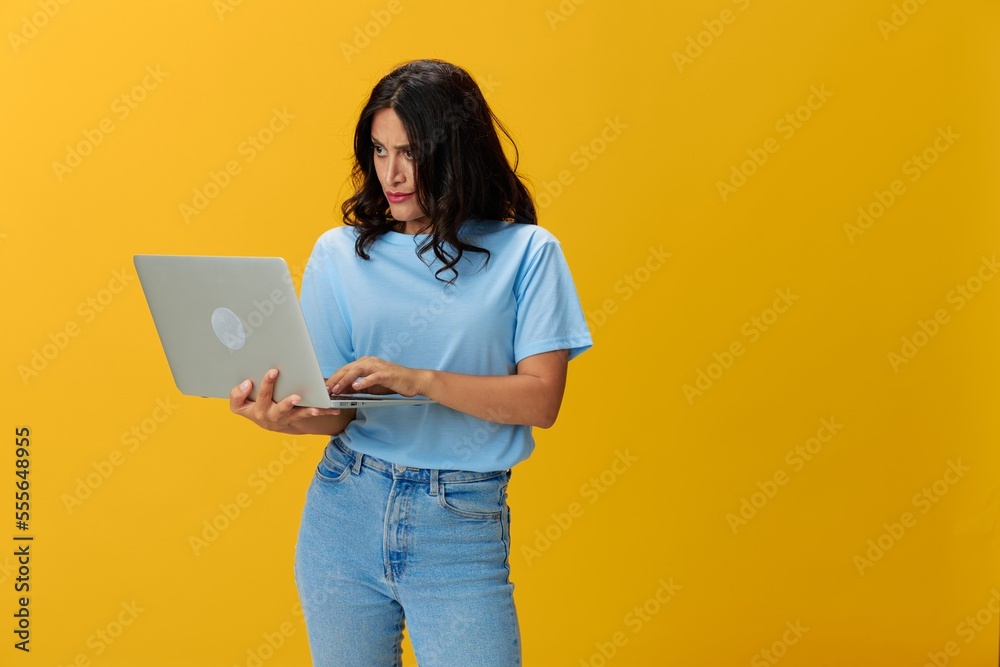 Woman freelancer with a laptop in her hands in a blue t-shirt and jeans on a yellow background smile signs gestures symbols, copy space, free background Woman freelancer with a laptop in her hands in a blue t-shirt and jeans on a yellow background smile signs gestures symbols, copy space, free background