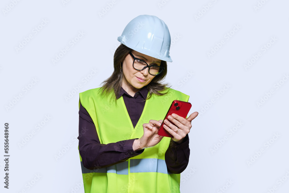 Woman industrial worker in helmet vest with smartphone Woman industrial worker in helmet vest with smartphone