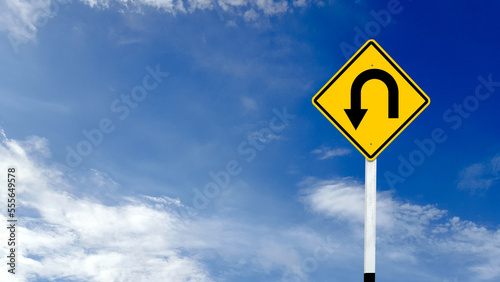 Yellow warn sign with left u turn arrow on blue sky background