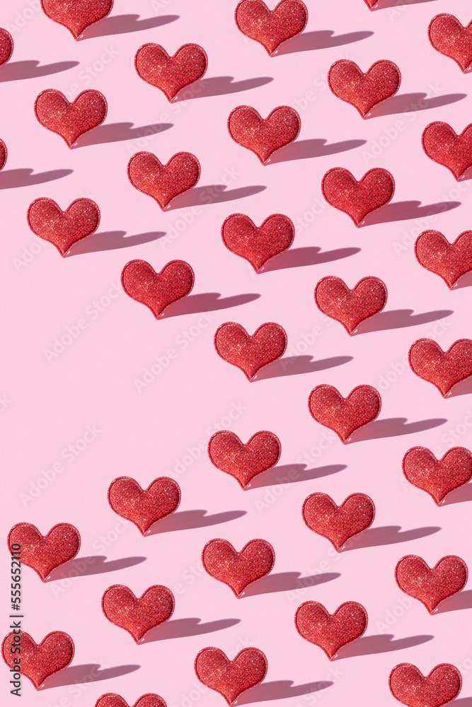 Pattern with red glitter heart shape on pink background with hard shadow. Valentines day minimalistic symbol love. Vertical format