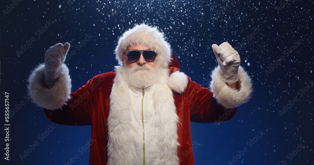 It is party time Cool santa claus wearing sunglasses dancing to music. Funny playful naughty grandfather with comic grimace, fooling around isolated on blue background It is party time Cool santa claus wearing sunglasses dancing to music. Funny playful naughty grandfather with comic grimace, fooling around isolated on blue background