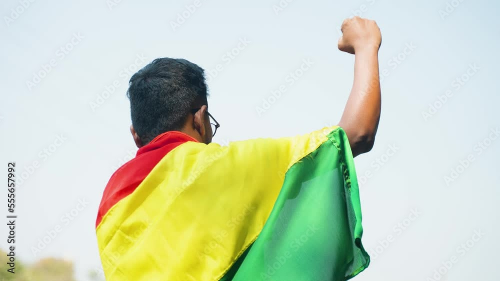 Back view shot of man with black history month flag on shoulder by raising fist hand - concept of freedom, justice and demonstration. Back view shot of man with black history month flag on shoulder by raising fist hand - concept of freedom, justice and demonstration.