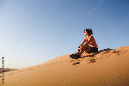 Sitting on a desert dune, the girl watching left photo