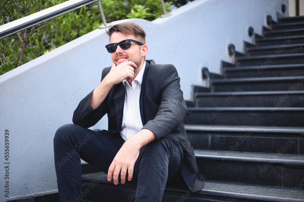 young business man sitting on staircase outdoors. young white man wearing a suit. young entrepreneur photoshoot.