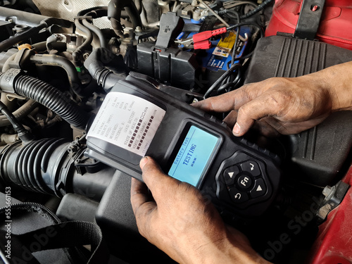Engineer holding Handheld device for Check up car battery life. battery tester concept.