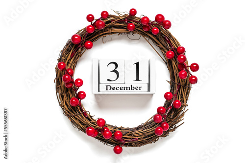 Christmas wreath decorated with red berries, wooden calendar date 31 December isolated on white background Concept of Christmas preparation, atmosphere Wishes card Hand made Christmas wreath Flat lay photo