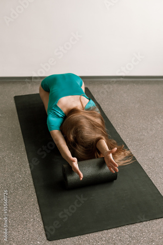 a beautiful girl does fitness in a bright hall with myofascial rolls