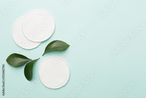 Quadro su tela Cotton reusable pads with leaves on color background. Top view.