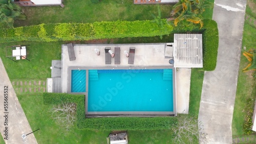 Swimming pool top view from a drone. Blue water in a swimming pool surrounded by a green fence for private relaxation in a hotel. Swimming pool top view without people on a hot sunny day