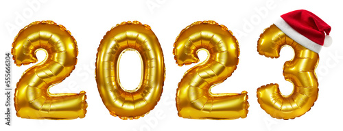 isolated golden letter foil balloons writing 2023 with santa hat in a composit shot.