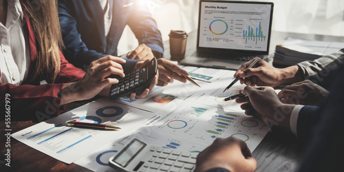 Business People Meeting using laptop computer,calculator,notebook,stock market chart paper for analysis Plans to improve quality next month. Conference Discussion Corporate Concept