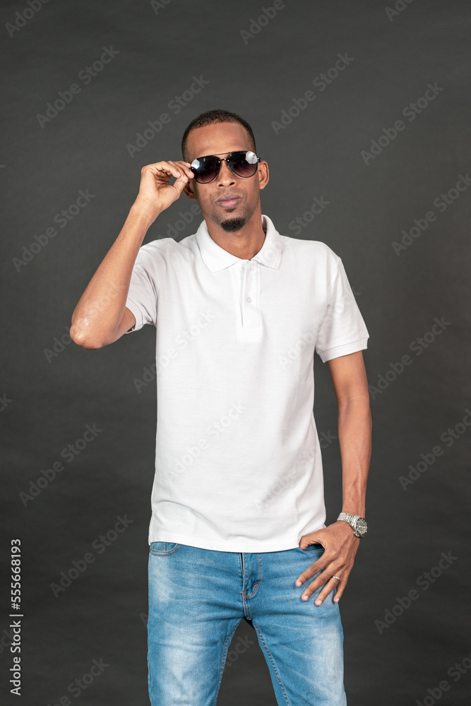 Fototapeta premium An african man with blank white polo shirt doing on the black background