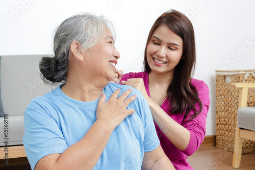 Daughter massaging shoulder for elderly Asian mother with shoulder pain. Family concept. Health care. Chronic shoulder pain treatment