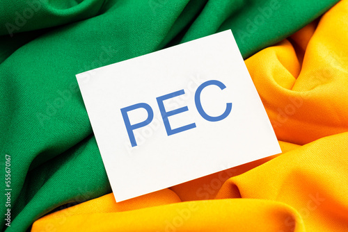 As iniciais PEC de Proposta de Emenda à Constituição escritas em um pedaço de papel em lingua portuguesa do Brasil. Tecidos verde e amarelo em referência a bandeira do Brasil. photo