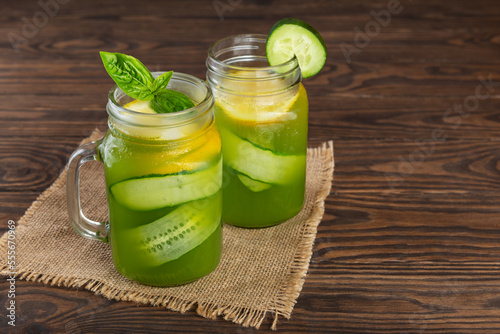 Cucumber lemonade with basil and lemon on a wooden table.