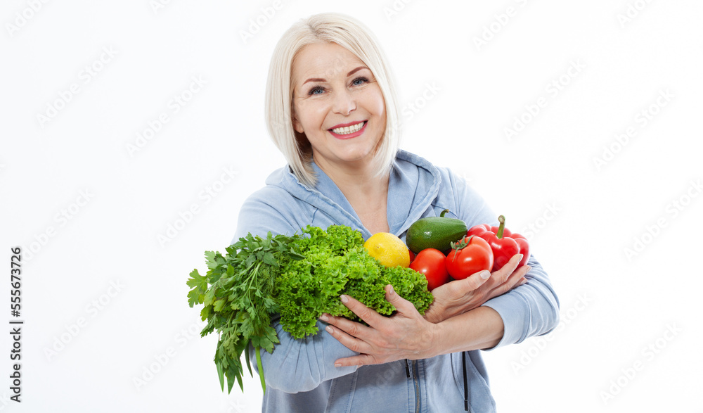 Happy woman with blond hair and beautiful smile holds a vegetables and herbs red pepper and green lettuce in her hands for a healthy diet. The concept of healthy eating vegetables. Happy woman with blond hair and beautiful smile holds a vegetables and herbs red pepper and green lettuce in her hands for a healthy diet. The concept of healthy eating vegetables.