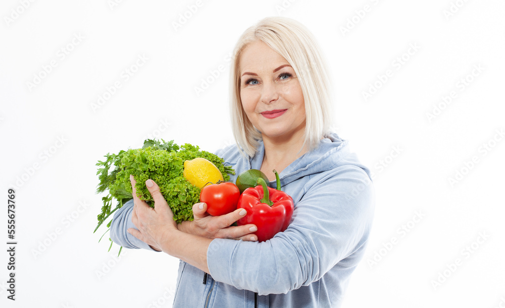 Happy woman with blond hair and beautiful smile holds a vegetables and herbs red pepper and green lettuce in her hands for a healthy diet. The concept of healthy eating vegetables. Happy woman with blond hair and beautiful smile holds a vegetables and herbs red pepper and green lettuce in her hands for a healthy diet. The concept of healthy eating vegetables.