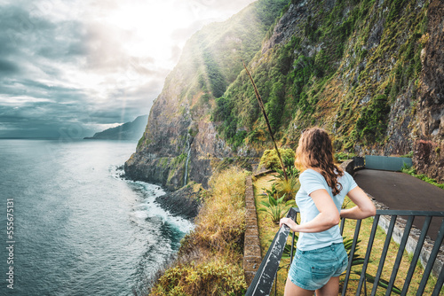 Sporty woman looking at waterfall flowing into the sea in atmospheric morning atmosphere. Viewpoint Véu da Noiva, Madeira Island, Portugal, Europe. photo