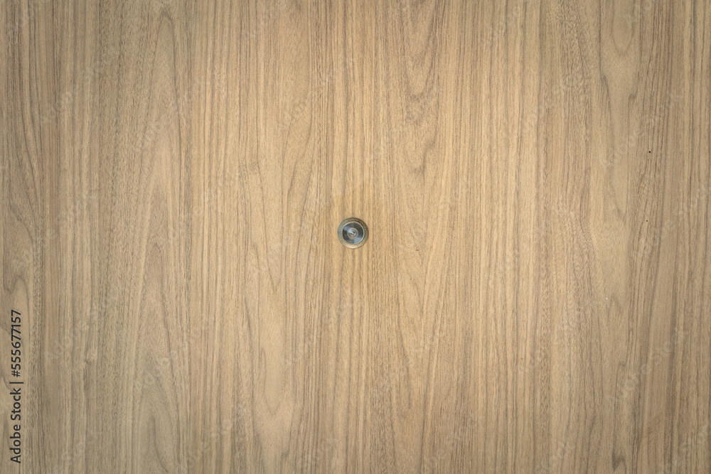 A peephole or eyehole on the wooden textured door. Interior and equipment object photo. A peephole or eyehole on the wooden textured door. Interior and equipment object photo.