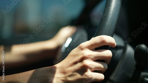 Closeup of person hands on steering wheel driving car. Woman driving a vehicle. Slow-motion driving commuting from work