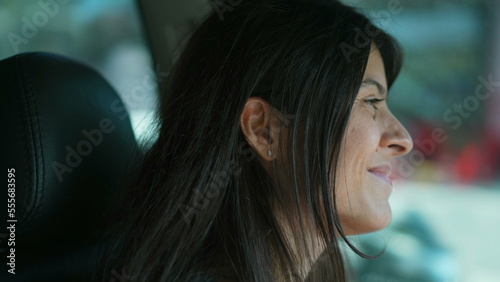 Happy female driver smiling while driving on city road. Closeup side view profile of a person inside auto vehicle in motion