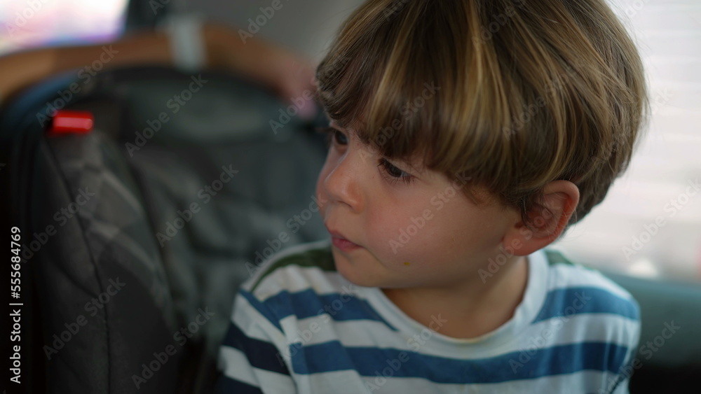 Little boy seated in car backseat traveling on road. Child on security seat inside auto vehicle Little boy seated in car backseat traveling on road. Child on security seat inside auto vehicle