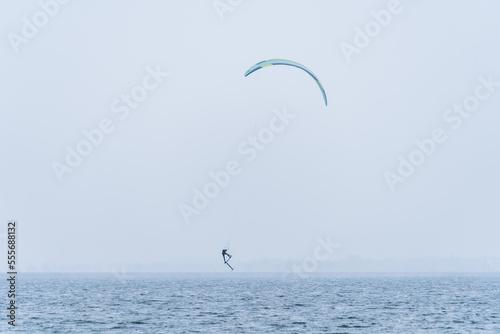 Hydrofoil Kitesurfer jumping in misty and cold winter conditions
