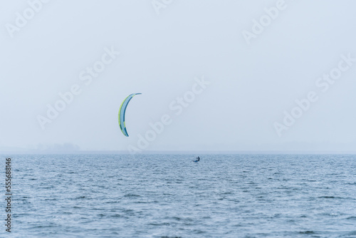 Wide shot of Hydrofoil Kitesurfer with kite in misty winter conditions