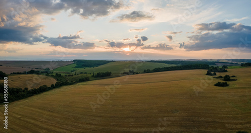 Aerial landscape view of yellow cultivated agricultural field with ripe wheat on bright summer evening