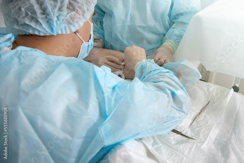 Top view of the operation on the leg with sterile medical instruments by a team of surgeons. Doctor professionally performs medical manipulation to treat varicose veins on the patient's leg