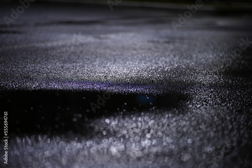 water drops and a puddle on wet pavement at night