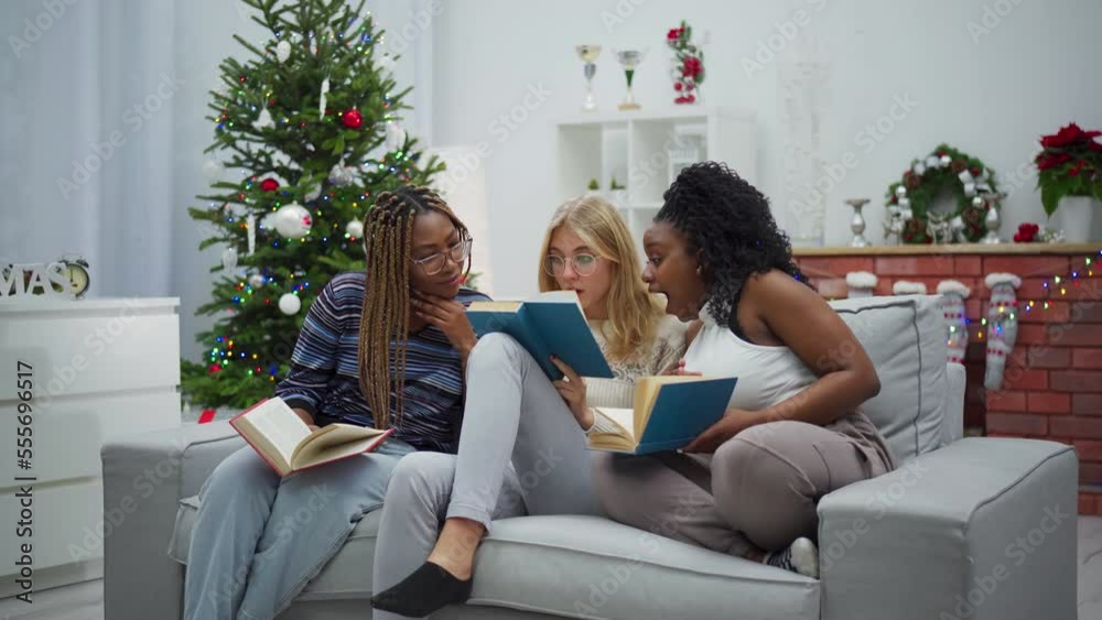 Two dark-skinned girls read a book together with one European woman. Two dark-skinned girls read a book together with one European woman.