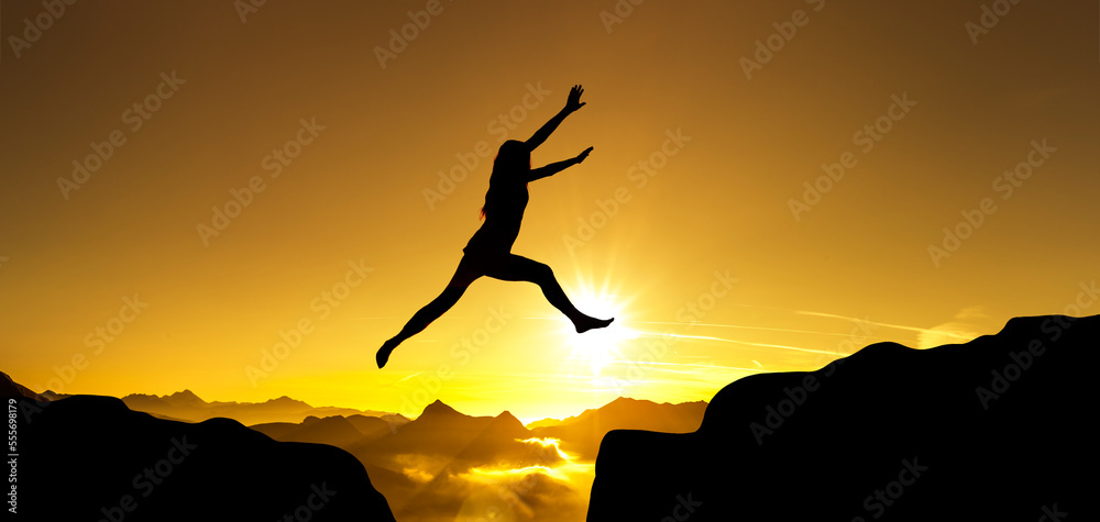 Silhouette einer Frau im Sprung über eine Klippe