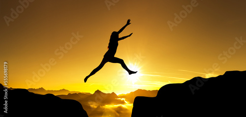 Silhouette einer Frau im Sprung über eine Klippe