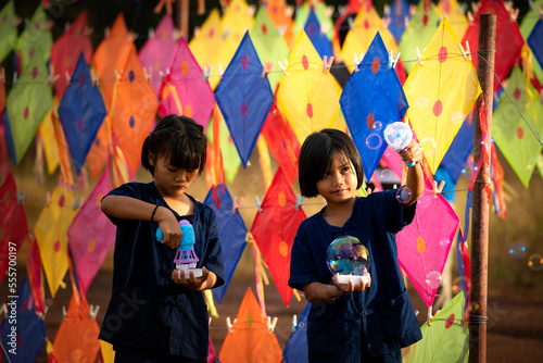 Village life in rural Thailand A little girls enjoy playing with lovely colorful kites strung on a wire