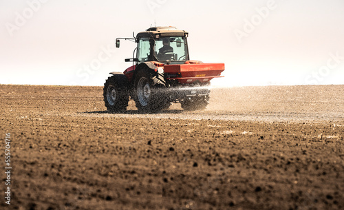 Fotografia Tractor spreading artificial fertilizers in field