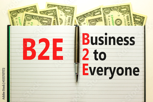 B2E business to everyone symbol. Concept words B2E business to everyone on white note on a beautiful background from dollar bills. Business and B2E business to everyone concept. Copy space.