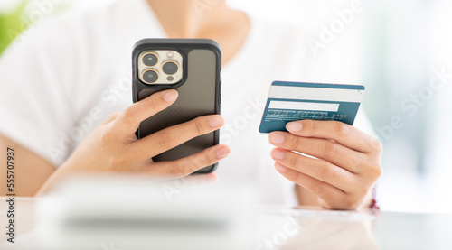 Close up shot of female hand holding credit card and using smartphone for online shopping