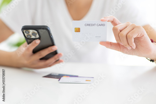 Close up shot of female hand holding credit card and using smartphone for online shopping