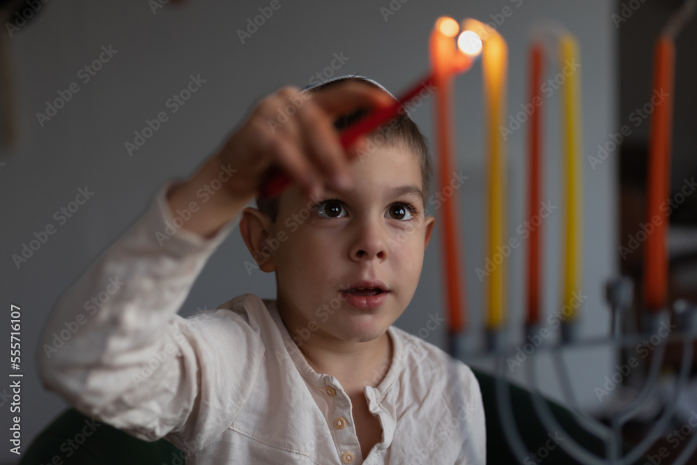 Little preschool boy lighting the Hanukkah candle on a menorah. Hanukkah lights. Jewish boy Little preschool boy lighting the Hanukkah candle on a menorah. Hanukkah lights. Jewish boy