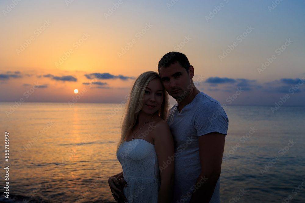 Silhouette of a young couple against the background of a sea sunset or sunrise. Silhouette of a man and a woman on the seashore or ocean.